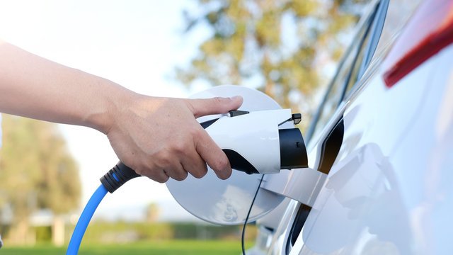 Hand plugging a charging connector into an electric vehicle