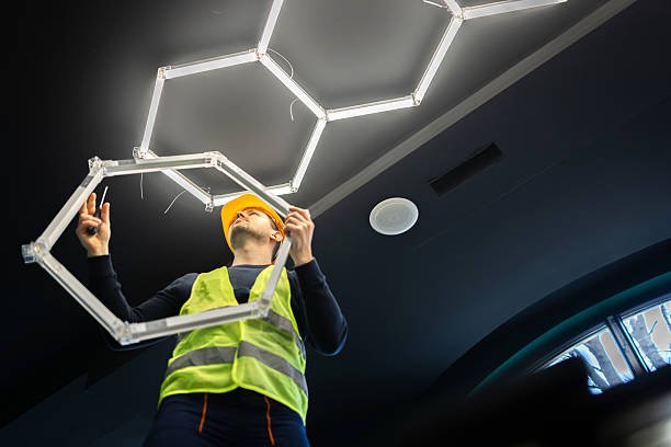 Worker installing a modern hexagonal LED ceiling light fixture